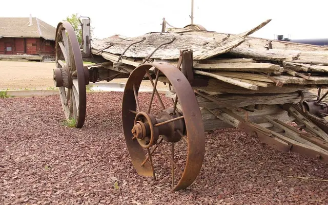 Old weathered wagon display with a red building behind